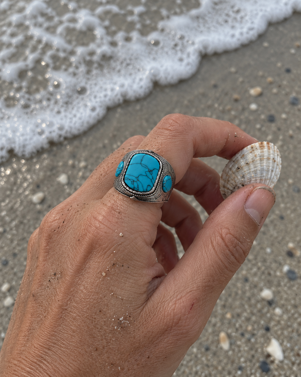 Blue Mesa Statement Ring worn on a hand holding a shell at the shoreline.
