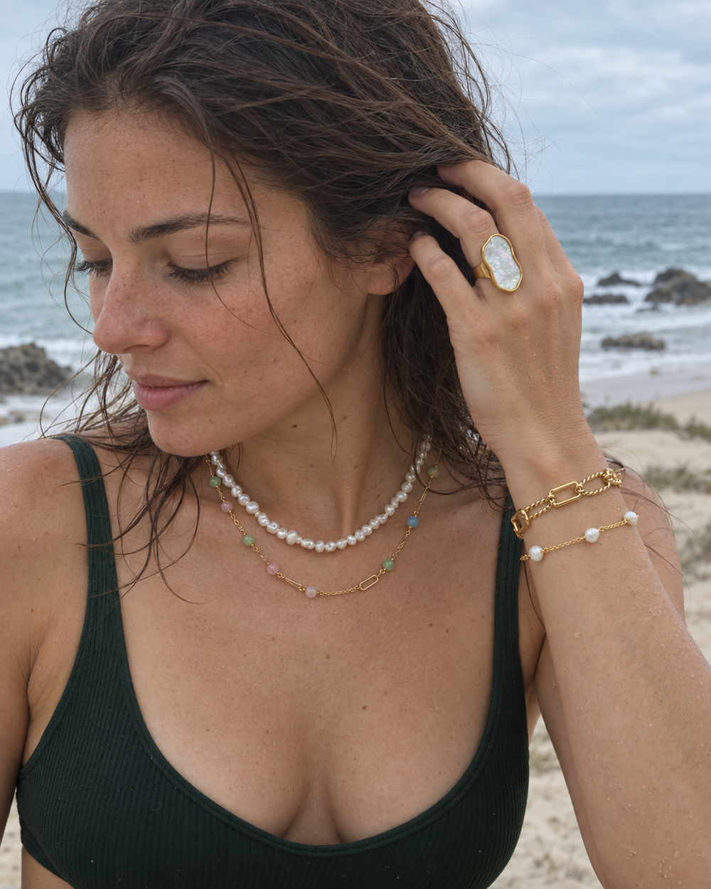 Moonpool Iridescent Ring with layered Whitewash, Pastel Tide and Shorelight jewellery in a candid beach portrait.