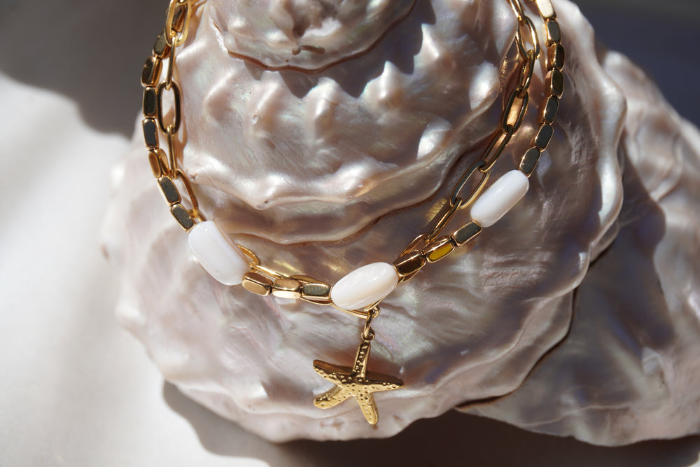 Alternate view: gold-tone link bracelet with white oval beads and a hanging starfish motif.