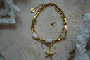 Gold-tone link bracelet with white oval beads and a hanging starfish motif.