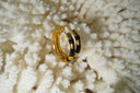 Gold-tone circular hoop earrings with black bands across their front sections.