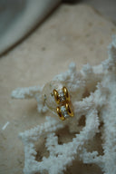Alternate view: gold-tone hoops with clear square accents set between rounded parallel edges.