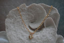 Gold-tone oval-link necklace with a front bar-and-ring detail and a smooth heart charm.