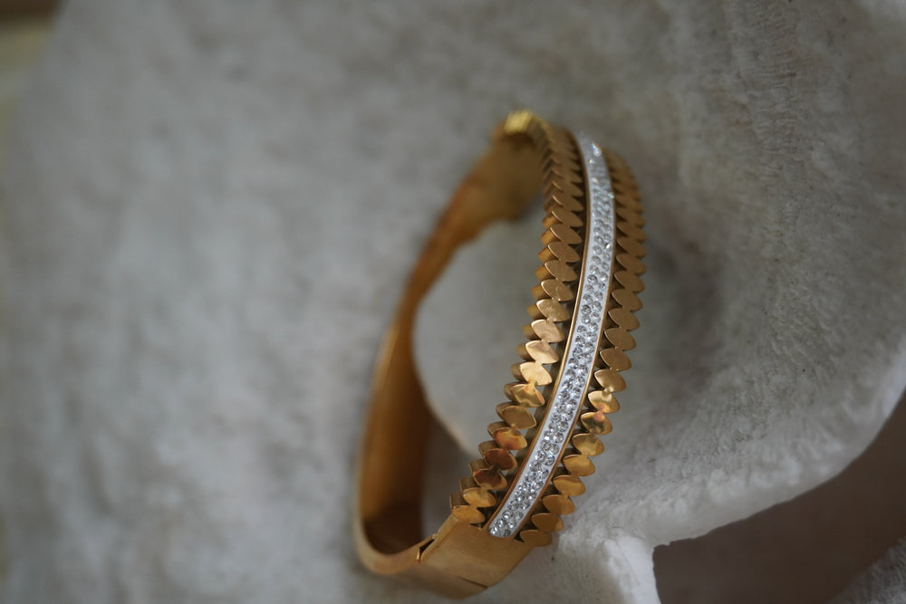 Alternate view: bangle with pointed gold-tone shapes framing a silver-tone central strip with rows of clear accents.