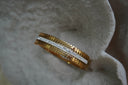 Bangle with pointed gold-tone shapes framing a silver-tone central strip with rows of clear accents.