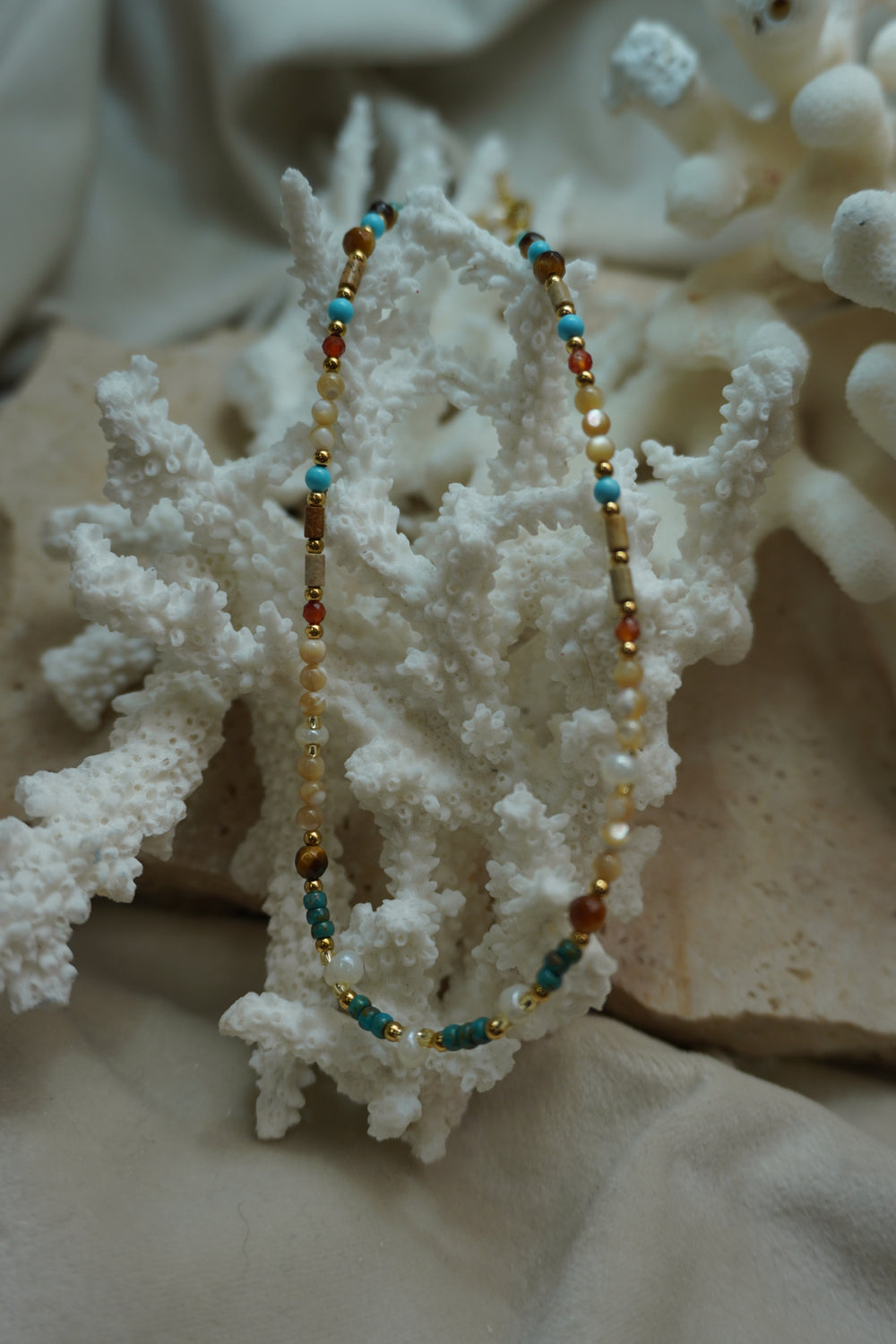 Mixed-bead necklace with cream, white, blue and brown beads, cylindrical sections and gold-tone spacers.