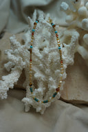 Mixed-bead necklace with cream, white, blue and brown beads, cylindrical sections and gold-tone spacers.