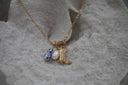 Gold-tone chain necklace with a boot charm, white oval bead and blue-and-white patterned beads on a circular connector.