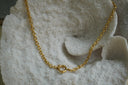 Gold-tone oval-link chain necklace with a prominent round clasp at the centre.