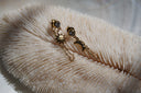 Gold-tone sun and crescent-moon stud earrings with faceted round accents and looping chains.