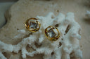 Alternate view: gold-tone stud earrings with clear square centres framed by flowing open circular curves.