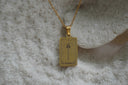 Gold-tone necklace with a rectangular The Hierophant pendant, staff with stacked crossbars and V lettering.