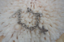 Silver-tone link bracelet with a textured starfish, fan-shell motif and pale shell-shaped charm.