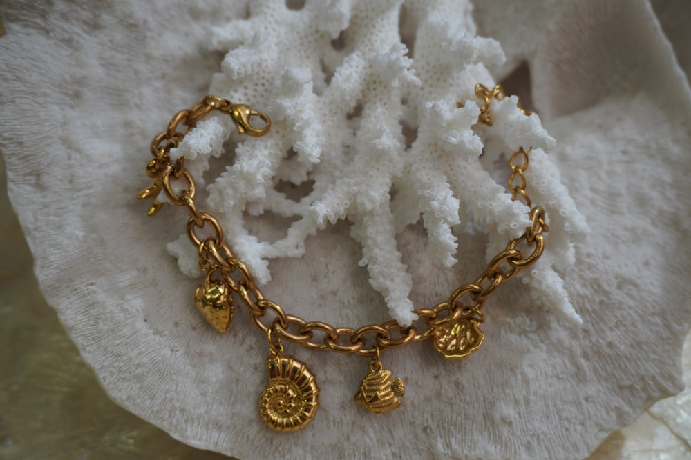 Gold-tone oval-link bracelet with strawberry, fish and shell charms.