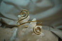 Gold-tone open cuff with a sweeping slender band and two spiral ends.