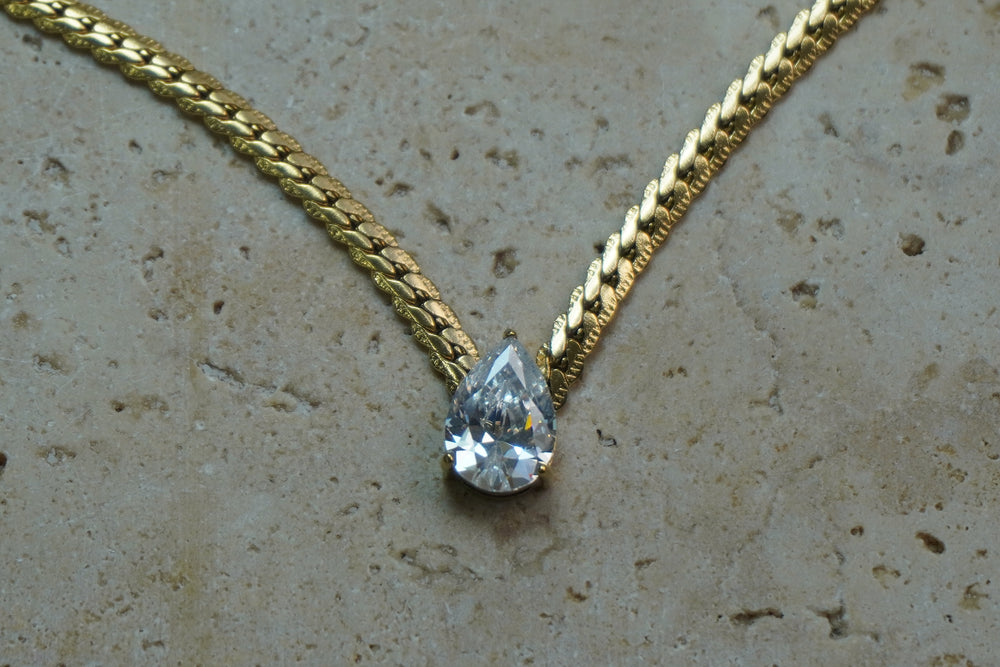 Alternate view: gold-tone textured chain necklace with a clear faceted teardrop centre.