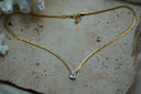 Gold-tone textured chain necklace with a clear faceted teardrop centre.