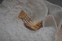 Gold-tone open cuff with parallel curved rails crossed by a diagonal centre rail.