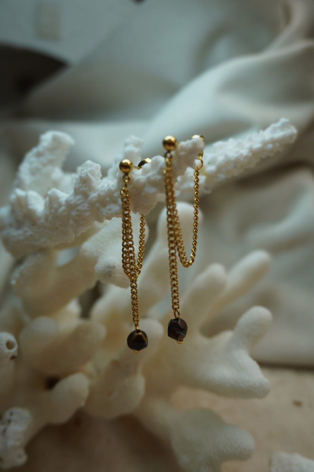Gold-tone ball-stud earrings with draped chain loops and long drops ending in dark brown faceted beads.