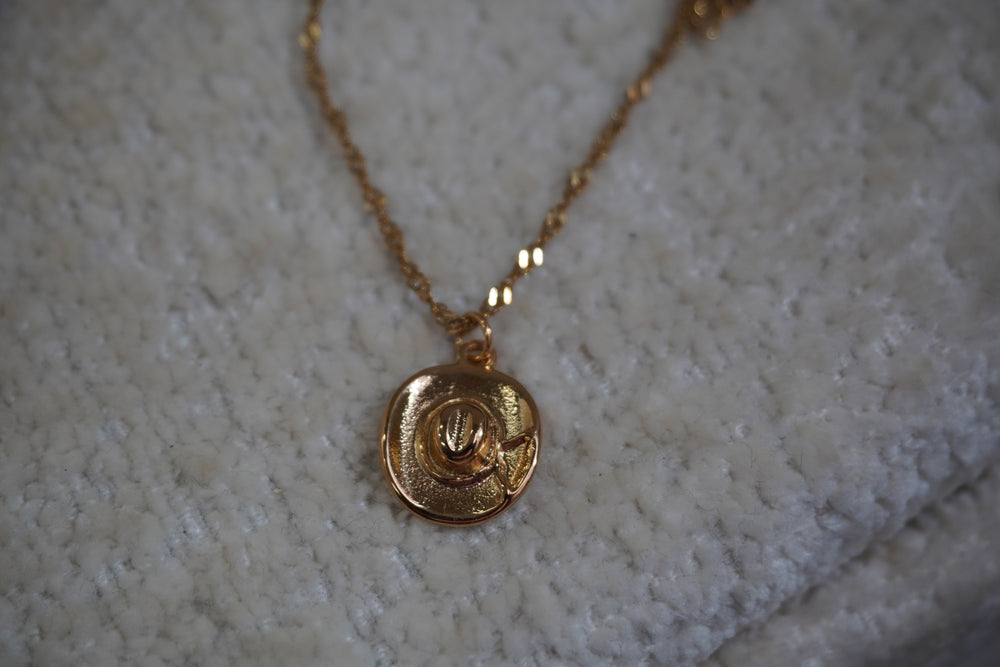 Alternate view: gold-tone necklace with a western hat pendant, curved brim, bow detail and twisting chain.