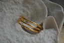 Gold-tone open cuff with three parallel bamboo-like rails and open spaces.