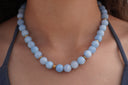 Blue Horizon Bead Necklace worn at the neckline, showing the rounded blue beads.