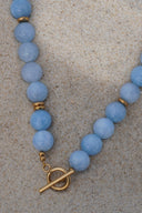Close view of powder-blue beads, gold-tone spacers and the ring-and-bar fastening.