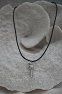 Alternate view: silver-tone revolver-shaped pendant with patterned edges on a black necklace cord.