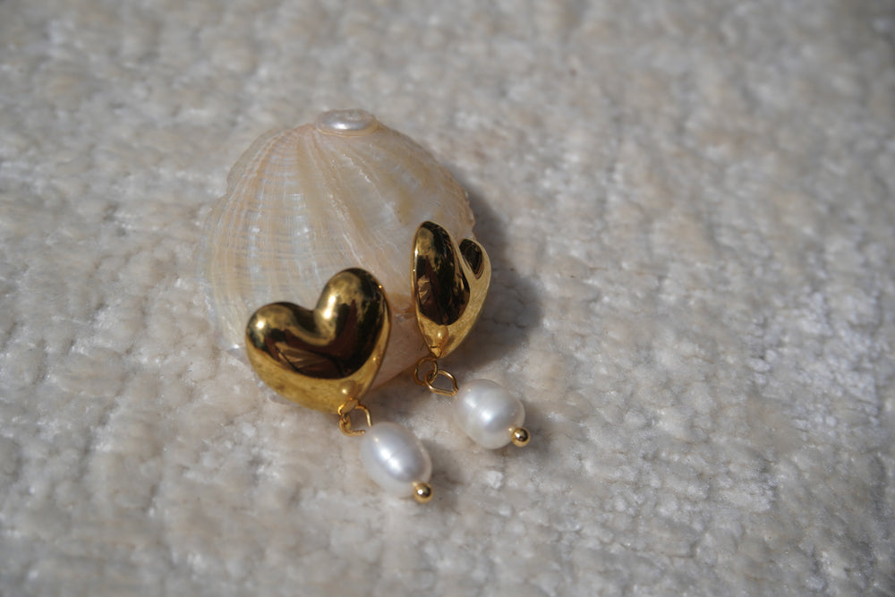 Rounded gold-tone heart stud earrings with white oval bead drops.