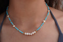 Worn view: necklace with faceted blue beads, spaced white beads, gold-tone spacers and a white centre cluster.