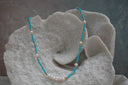 Necklace with faceted blue beads, spaced white beads, gold-tone spacers and a white centre cluster.