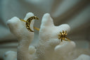 Gold-tone open cuff with a dimpled crescent moon and a sun with spiral centre and curved rays.