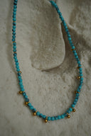 Blue-green beaded necklace with spaced gold-tone round accents.