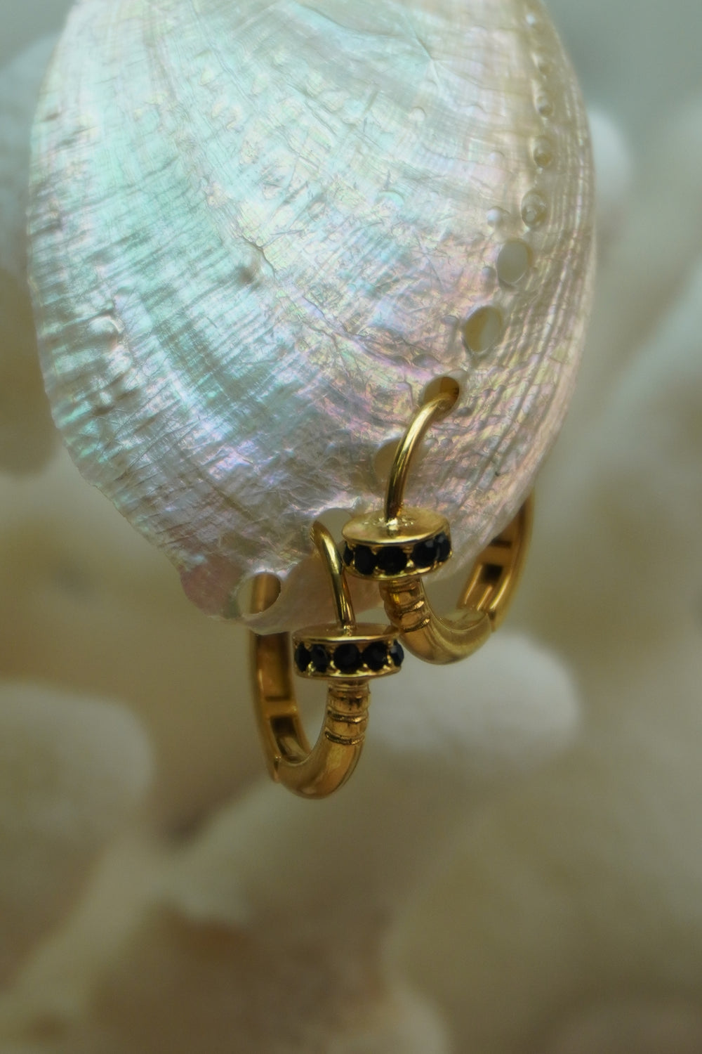 Alternate view: gold-tone hoops with ridged sections and disc-like collars edged with dark accents.