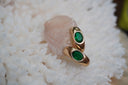 Alternate view: elongated gold-tone earrings with oval green faceted centres and smooth curved surfaces.