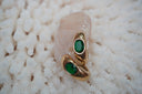 Elongated gold-tone earrings with oval green faceted centres and smooth curved surfaces.