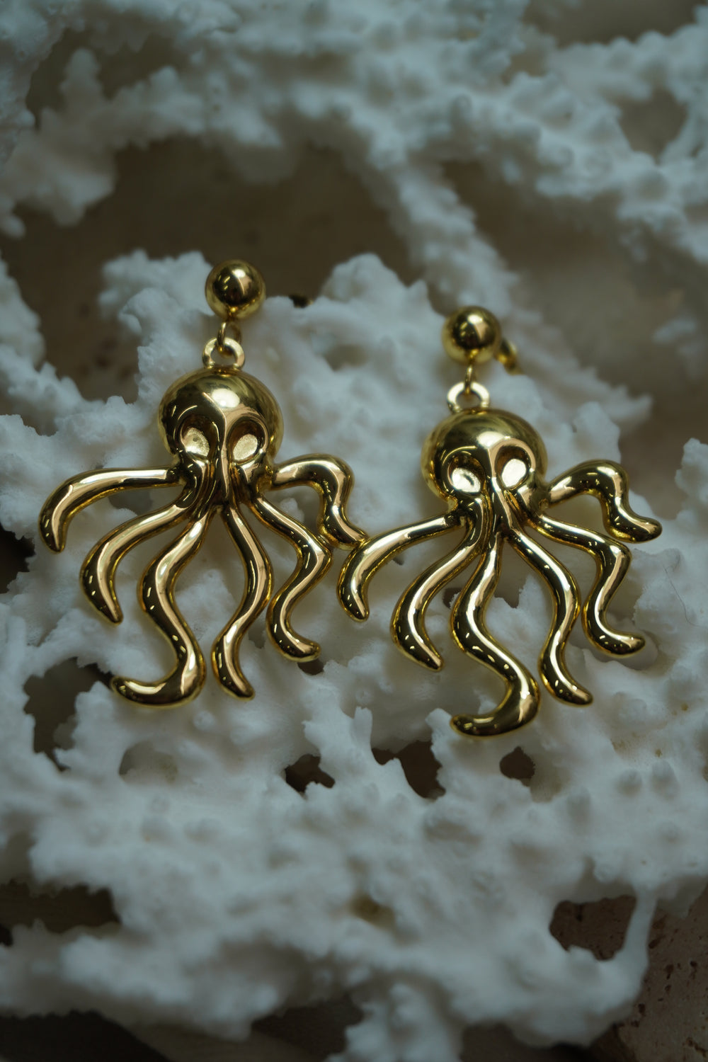 Gold-tone octopus drop earrings with curling tentacles beneath smooth ball studs.