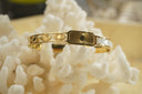 Alternate view: gold-tone bangle with a radiating rectangular centre, pale panels and smaller eye-shaped motifs.