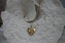 Gold-tone necklace with a smooth rounded heart pendant and a fine chain with twisted-looking links.
