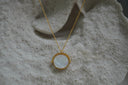 Gold-tone chain necklace with a pale reflective circular pendant.