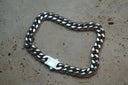 Silver-tone curb-chain bracelet with broad links and a flat clasp.