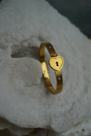 Alternate view: gold-tone bangle with a heart-shaped centre and dark keyhole detail.