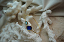 Alternate view: gold-tone open cuff with a small aqua and a larger deep-blue rounded square faceted accent.