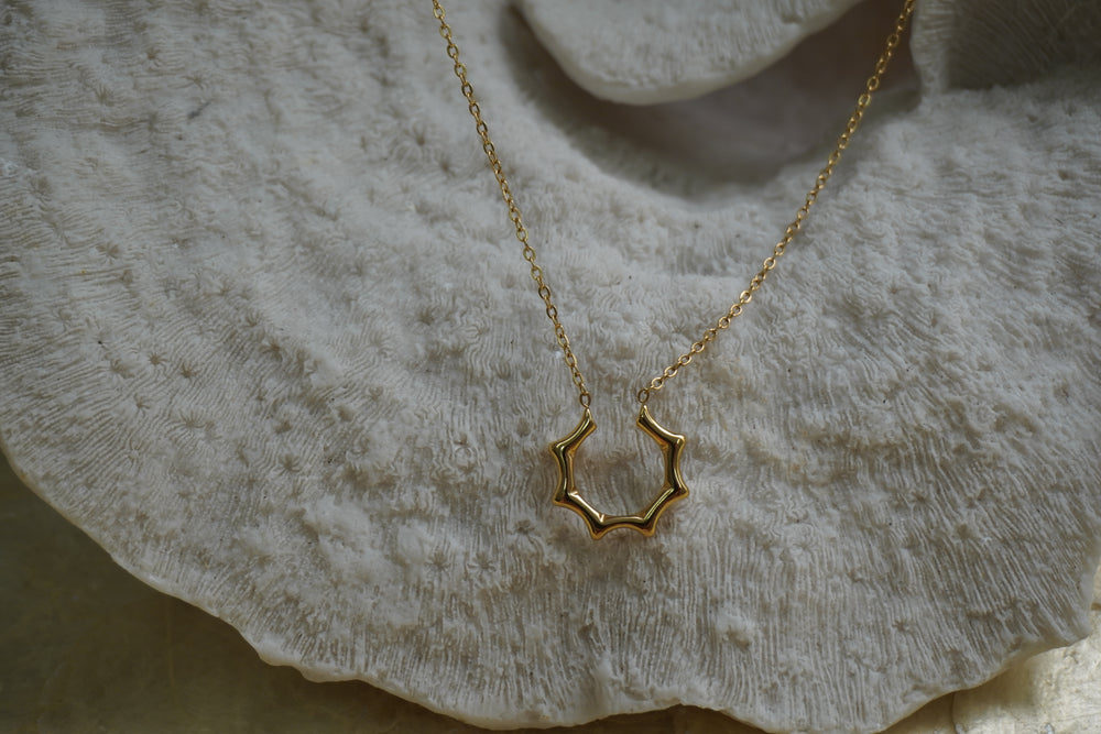 Gold-tone necklace with an open scalloped halo shape attached to a fine chain.