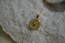 Alternate view: gold-tone necklace with a textured circular compass-star token.