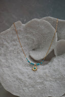 Gold-tone elongated-link necklace with blue beads, gold-tone spacers and a blue-centred sunburst pendant.