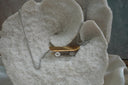 Skateboard necklace with a gold-tone deck, silver-tone wheel details and a silver-tone chain.