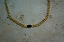 Gold-tone chain necklace with a smooth dark horizontal oval centre in a narrow gold-tone border.