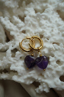 Gold-tone hoop earrings with deep purple heart-shaped bead drops and small gold-tone ball details.
