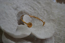 Slender gold-tone open cuff with a ridged shell shape at each end.